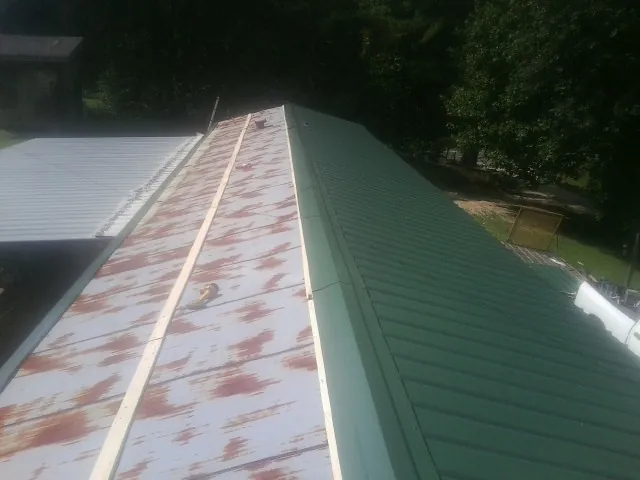 Old rusted panels beside newly installed green metal roofing — Wind Damage Roof Repair by Roofing Brothers in Rosemead