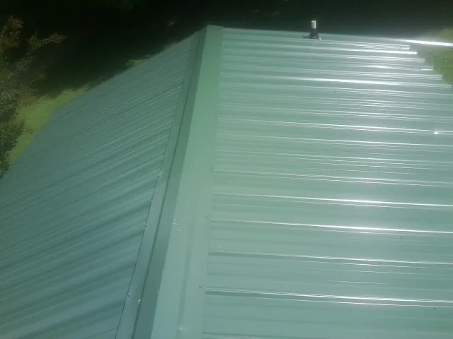 New green metal panels meeting at the ridge of a roof — Flat Roof Repair work by our crew in Rosemead