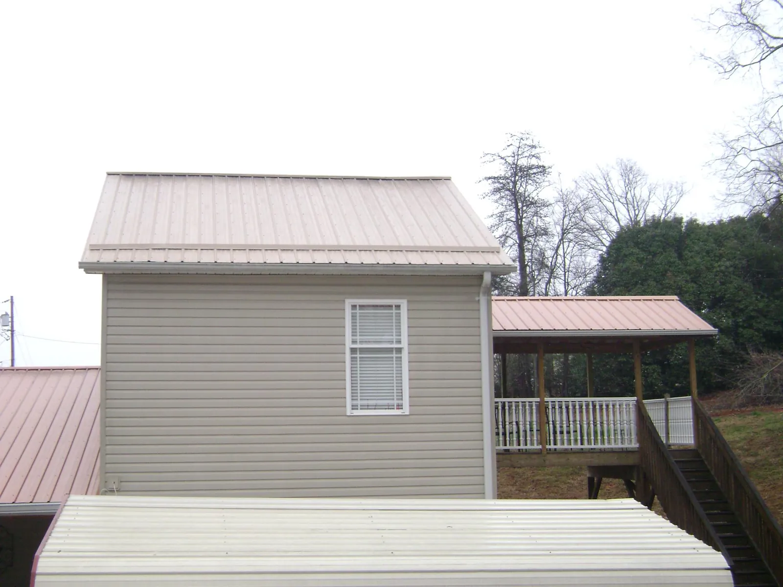 Tan metal roofs on a two story addition and attached porch, from a Roof Replacement job in Rosemead